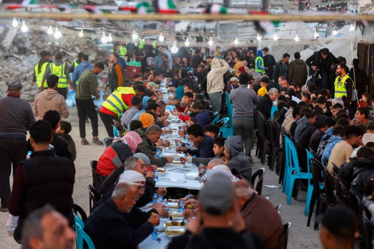 Palestinians gather for a mass fast-breaking iftar meal organized by the Turkish IHH Foundation, amid the rubble of destroyed buildings in Gaza City on February 18, 2026. Little Ramadan lanterns and string lights appeared on streets lined with collapsed buildings and piles of rubble in Gaza City, bringing joy and respite as Islam's holiest month began -- the first since October's ceasefire. (AFP)