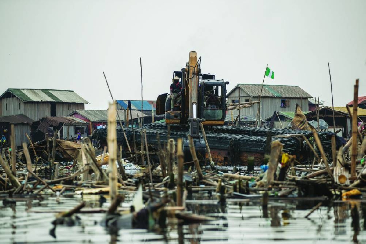 An excavator demolishes houses in Makoko, a floating slum in Lagos, on January 9, 2026. Authorities have demolished hundreds of wooden shacks in Makoko, Africa’s largest and most iconic floating slum, which is built on stilts above the lagoon in the heart of Lagos. The operation is part of an ongoing campaign to remove what officials describe as illegal structures and reclaim waterfront land for modern real-estate developments. (Photo by TOYIN ADEDOKUN / AFP)