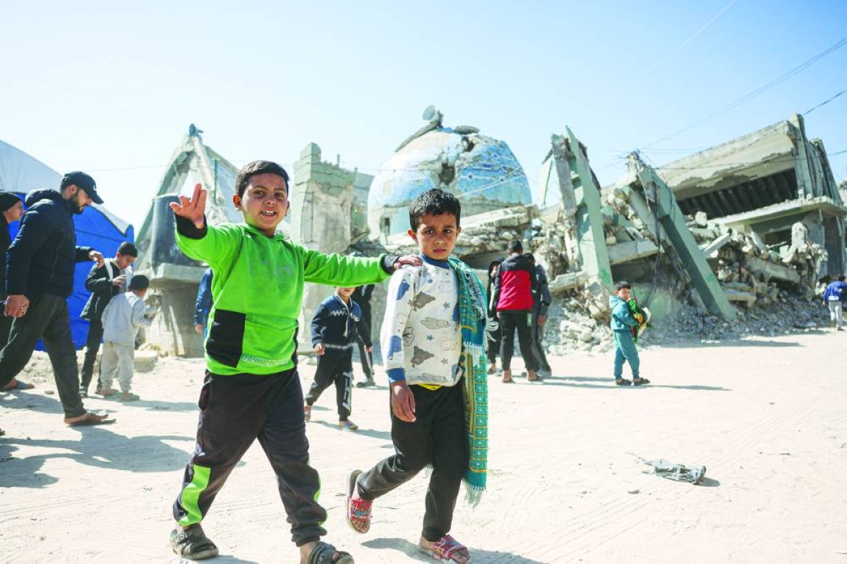 Two displaced Palestinian boys, one carrying a pray mat of his shoulder, leave following the first Friday noon prayers of the holy month of Ramadan, outside the destroyed Al-Huda Mosque, in Khan Yunis in the southern Gaza Strip on February 20, 2026. Nearly all of Gaza's 2.2 million residents were displaced at least once during the more than two years of war between Israel and Hamas, sparked by the latter's unprecedented October 7 attack on Israel. (Photo by Bashar Taleb / AFP)