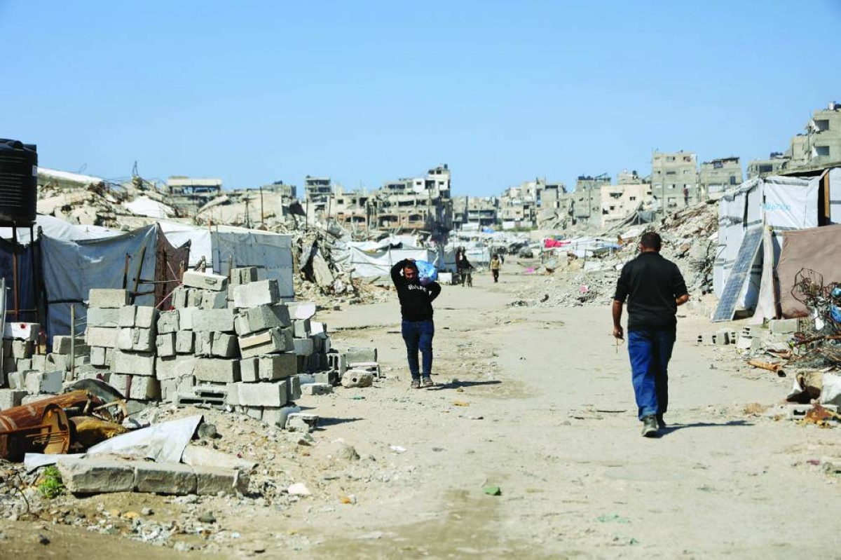 Displaced Palestinians walk along what used to be a main road, past tents housing displaced families erected between the rubble of homes and businesses destroyed by the Israeli military, in the Sheikh Radwan neighborhood of Gaza City, yesterday.
