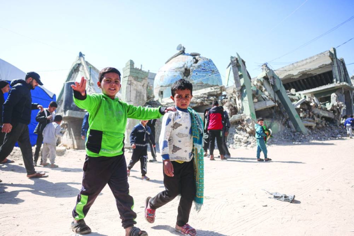 Two displaced Palestinian boys, one carrying a pray mat on his shoulder, leave following the first Friday noon prayers of the holy month of Ramadan, outside the destroyed Al-Huda Mosque, in Khan Yunis in the southern Gaza Strip, yesterday.