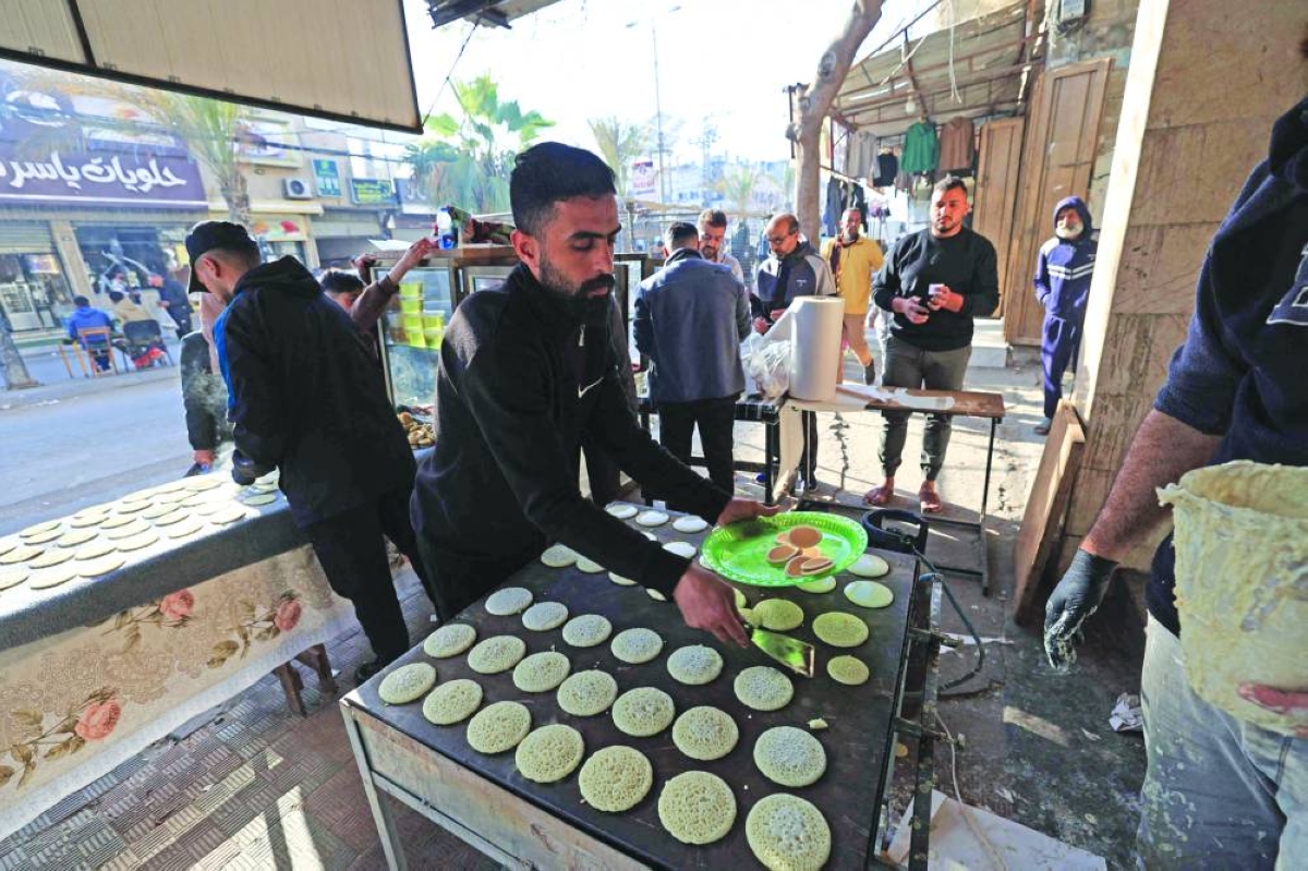 A displaced Palestinian prepares to sell a popular dessert qatayef during the holy month of Ramadan, at a corner market in an attempt to overcome harsh living conditions in Nuseirat in the central Gaza Stri, yesterday.