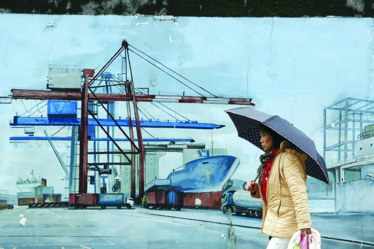 A woman walks past a painting outside at Keelung port, northern Taiwan. US trading partners in Asia started weighing fresh uncertainties on Saturday after President Donald Trump vowed to ‌impose a new tariff on imports, hours after the Supreme Court struck down many of the ​sweeping levies he used to ‌launch a global trade war. (File:Picture)