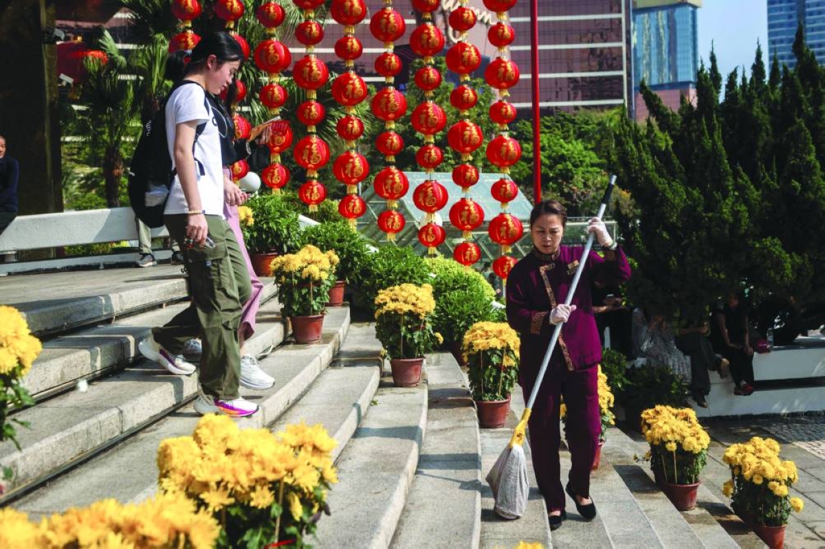 A tourist leaves hotel Lisboa while a member of staff cleans the steps during the Chinese New Year holiday in Macau on Friday. (AFP) 