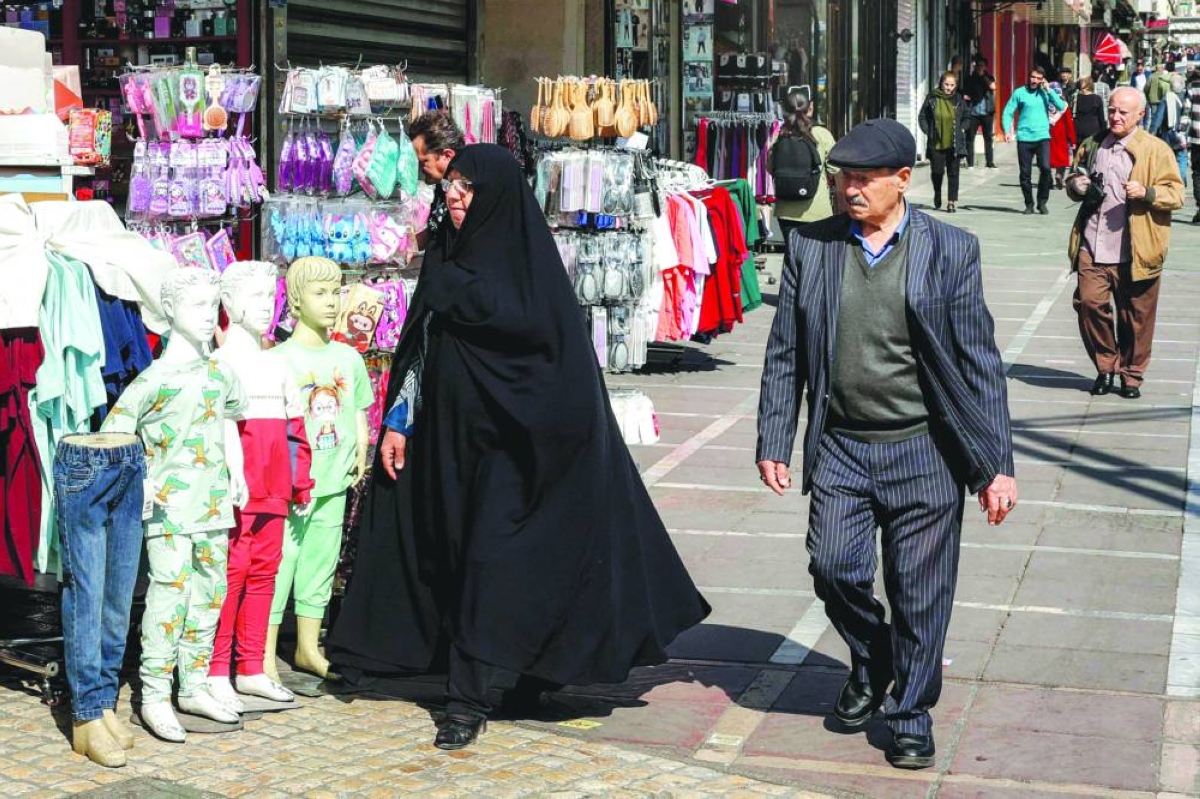 A woman and man walk along a main street in Tehran on February 21, 2026. (AFP)