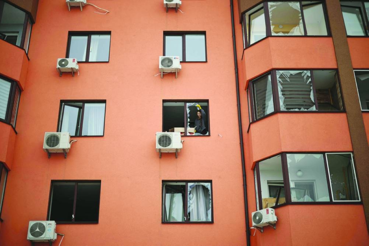 A local resident removes glass shards from a broken window in a residential buidling following an air attack in Sofiivska Borshchagivka, Kyiv region Sunday, amid the Russian invasion of Ukraine.