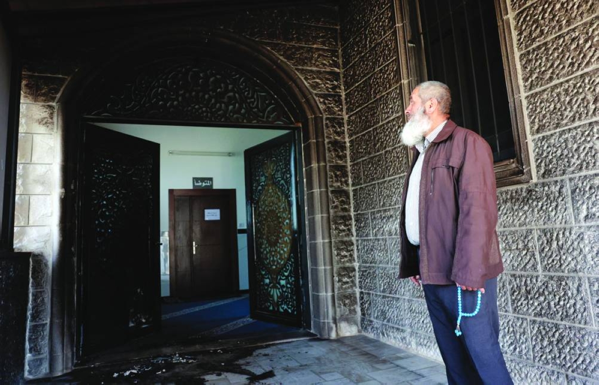 A Palestinian man, holding Misbaha prayer beads, inspects the debris at a mosque, which was damaged by Israeli settlers, in West Bank village of Surra, near Nablus in the occupied West Bank, Monday.