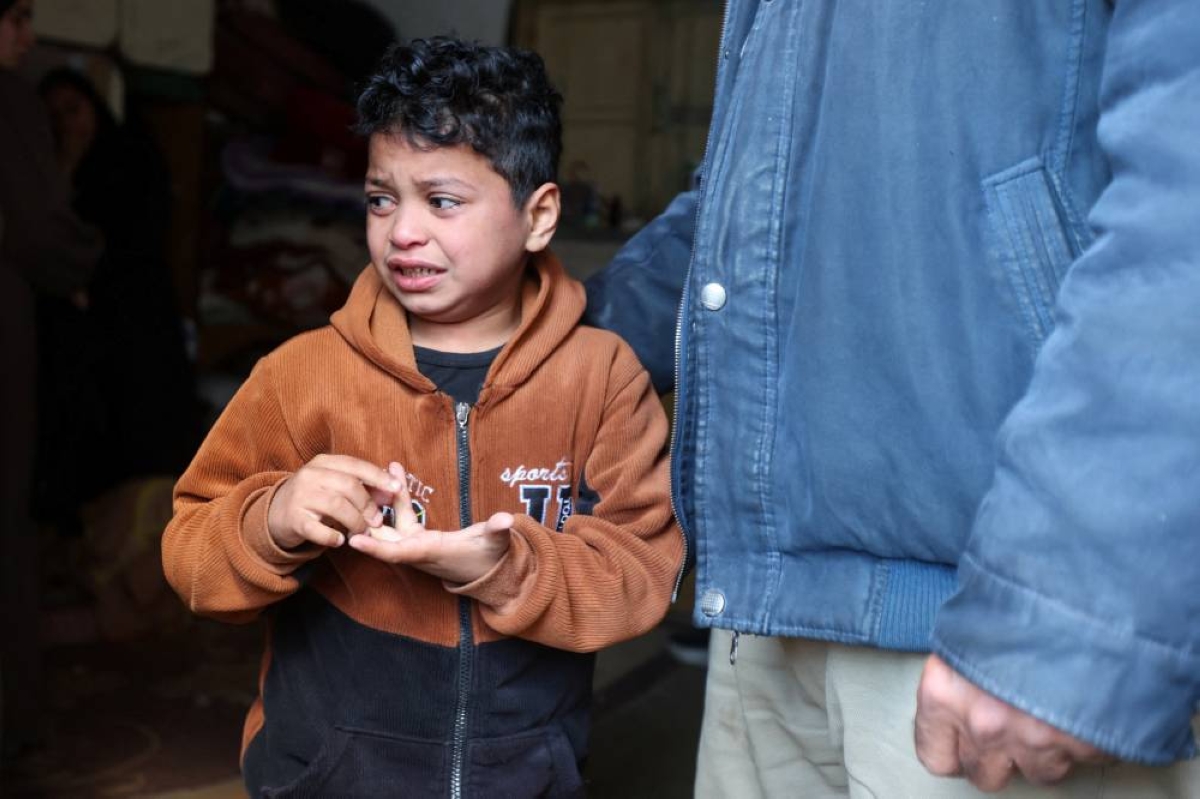 
Relatives of Palestinian policeman Khaled al-Zayan, who was killed in an Israeli strike on a checkpoint, according to medics, mourn during his funeral in Khan Younis in the southern Gaza Strip, yesterday. Right: Son of Palestinian policeman Khaled al-Zayan, who was killed in an Israeli strike on a checkpoint, reacts during his funeral in Khan Younis. 