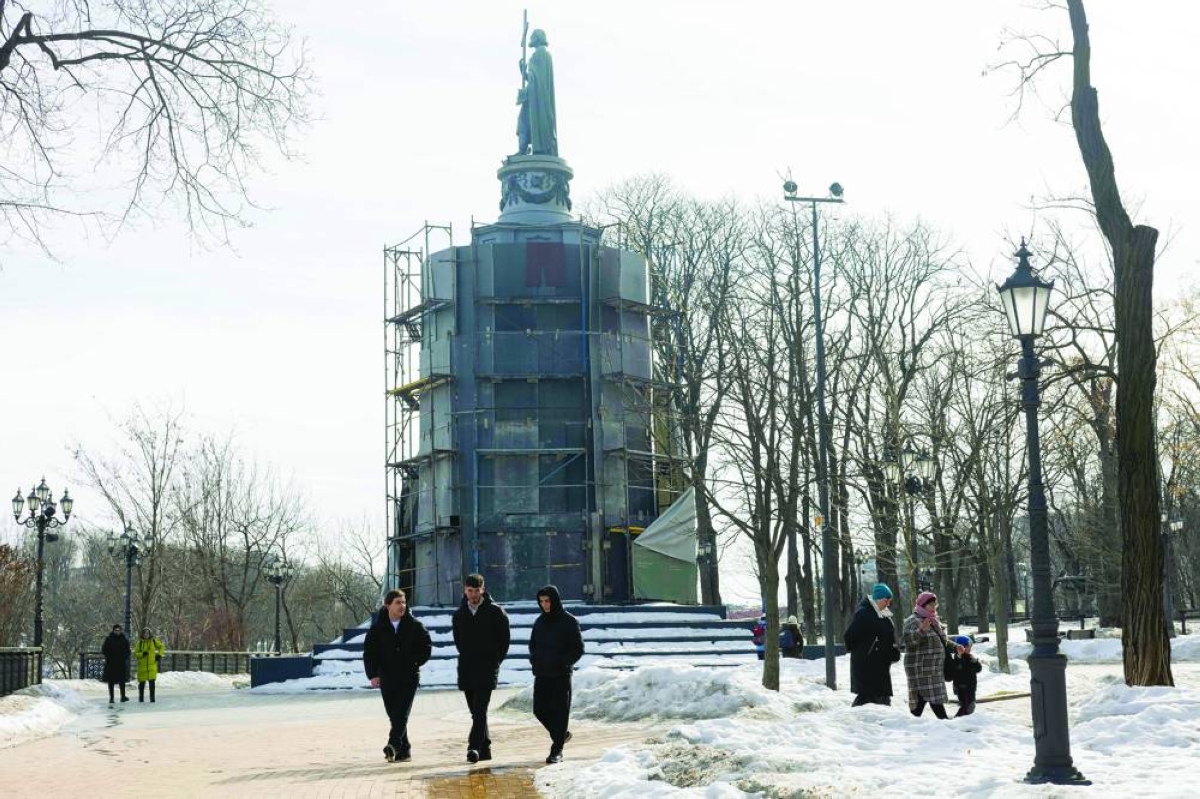 
People walk by the monument to Saint Volodymyr covered in scaffolding in Kyiv amid the Russian invasion of Ukraine. 