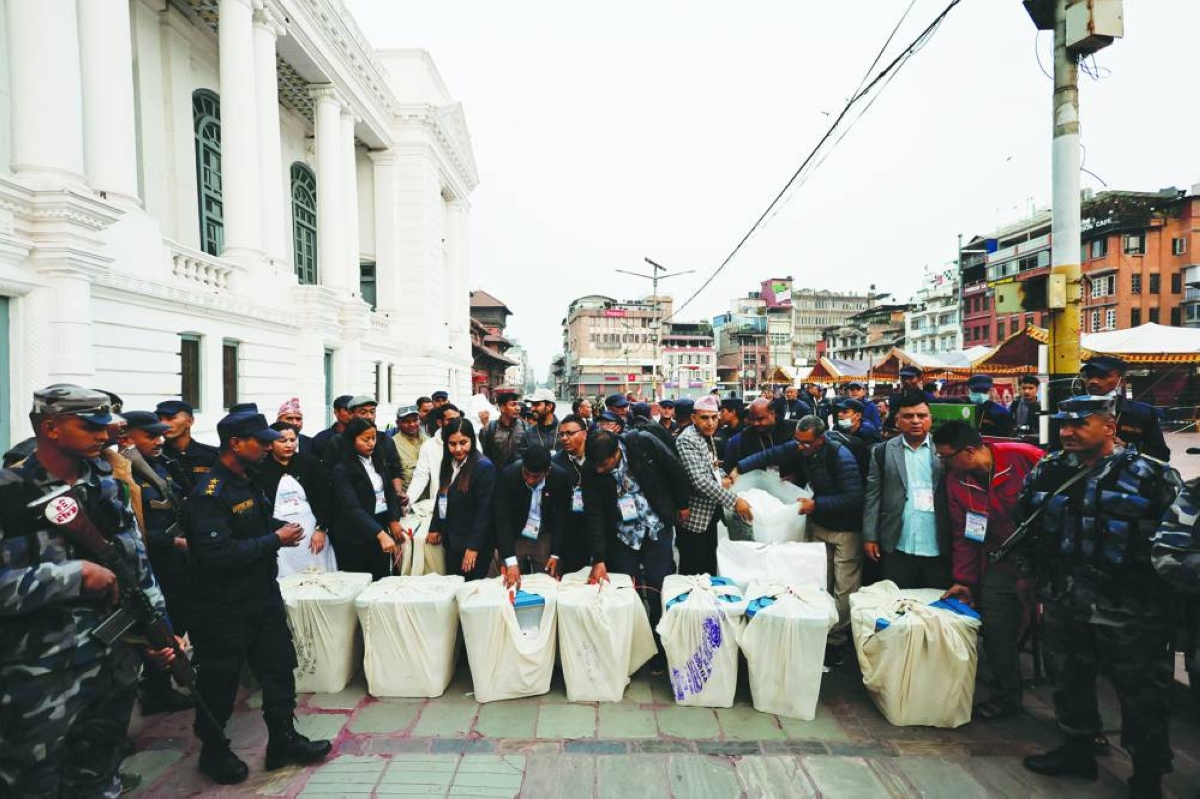 Polling officials stand next to the ballot boxes after voting in the country's general election ended, at Bashantapur Durbar Square in Kathmandu, Thursday.