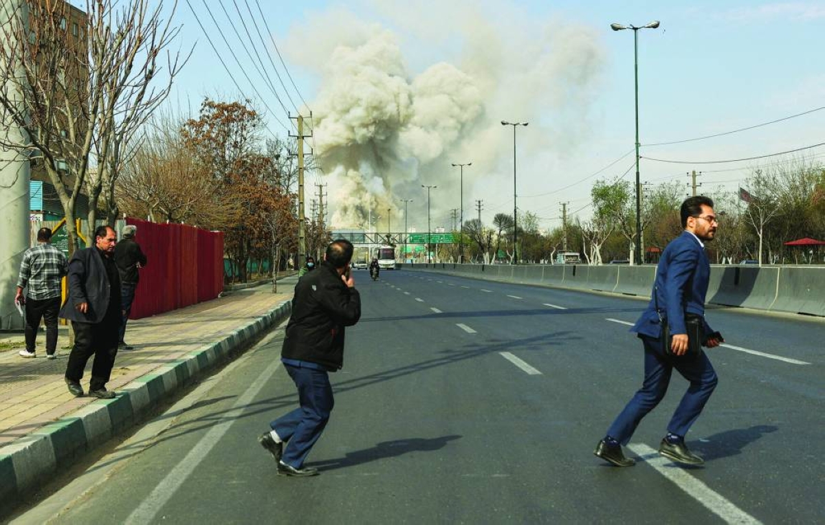 People run as smoke rises following an explosion in Tehran Thursday. Reuters