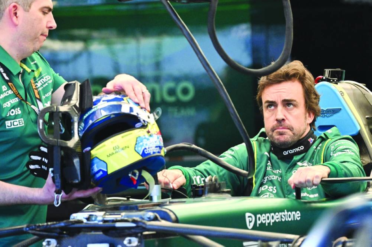 Aston Martin's Spanish driver Fernando Alonso inspects his car with team mechanics in the garage ahead of the Formula One Australian Grand Prix at Melbourne’s Albert Park on March 5, 2026. (AFP)