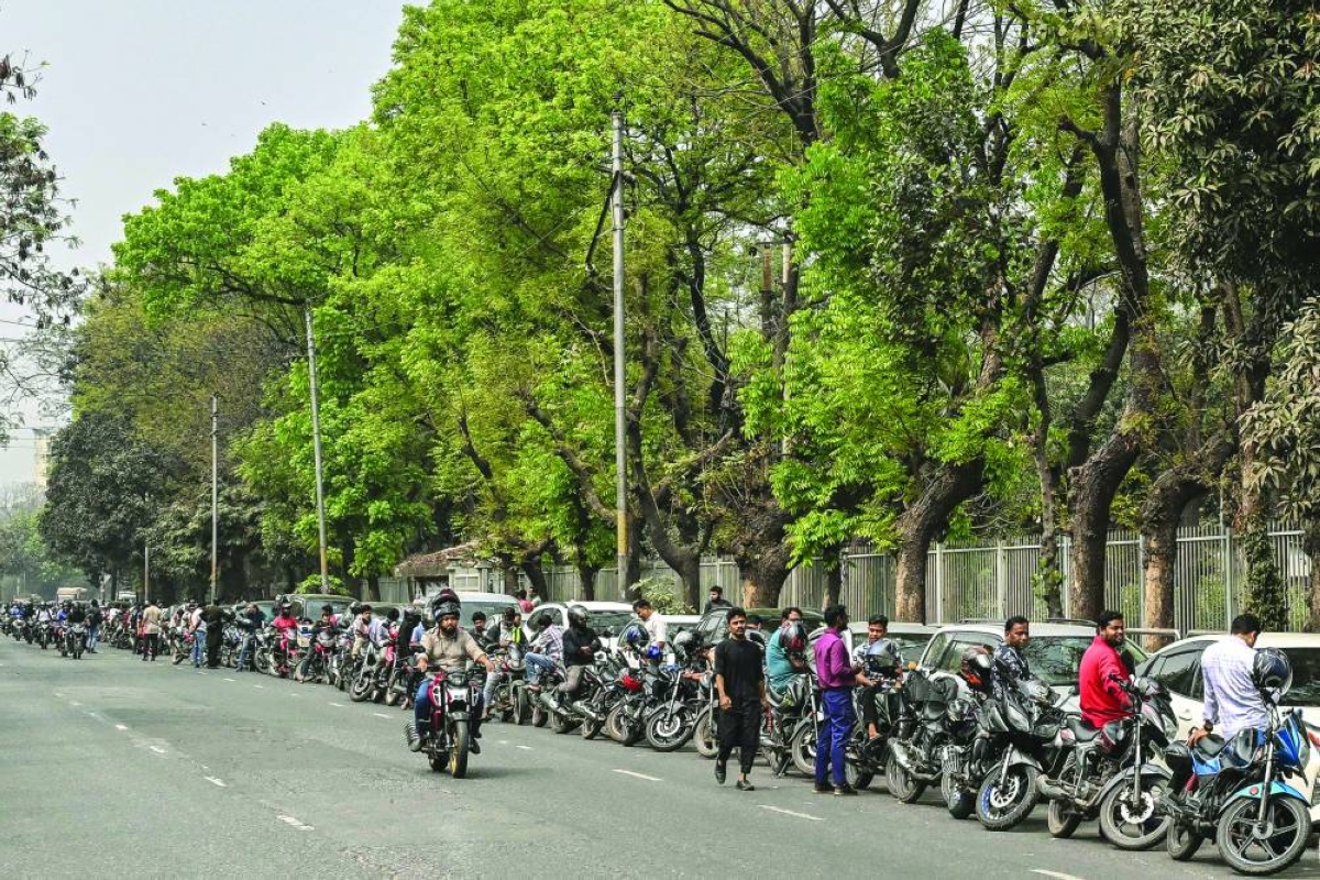 People wait in a queue to refuel their vehicles near a fuel station in Dhaka Sunday. (AFP)