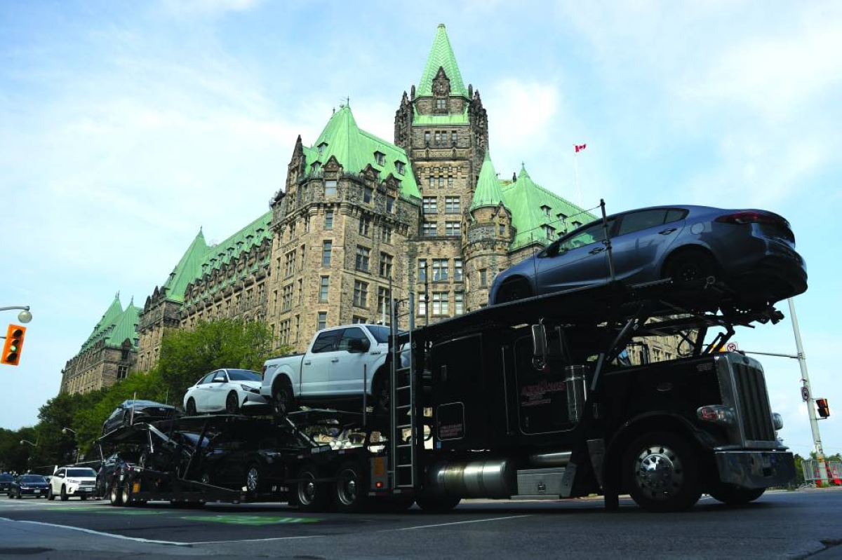 
An auto carrier drives by government buildings in Ottawa. 