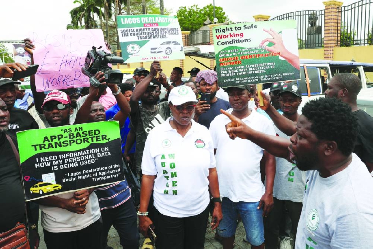 People hold signs as Nigerian ride-hailing drivers working with Uber, Bolt and inDrive protest in Lagos over low fares, urging the Lagos State Assembly to mandate higher rates amid surging petrol prices linked to the Iran conflict, in Lagos, Wednesday. (Reuters)