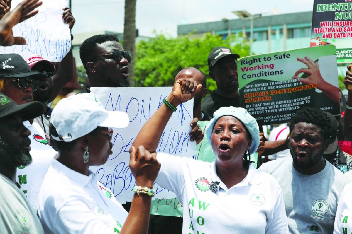 People hold placards as Nigerian ride-hailing drivers working with Uber, Bolt and inDrive protest in Lagos over low fares, urging the Lagos State Assembly to mandate higher rates amid surging petrol prices linked to the Iran conflict, in Lagos, Wednesday. (Reuters)