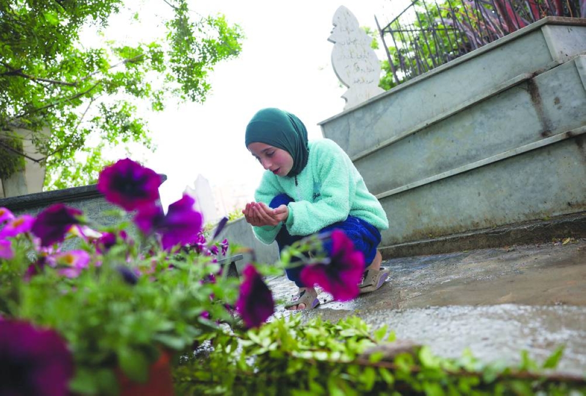 A displaced girl from Tyre prays in front of a grave at a cemetery in Sidon, Lebanon, on the day of Eid al-Fitr, following an escalation between Hezbollah and Israel amid the US-Israeli conflict with Iran. Reuters