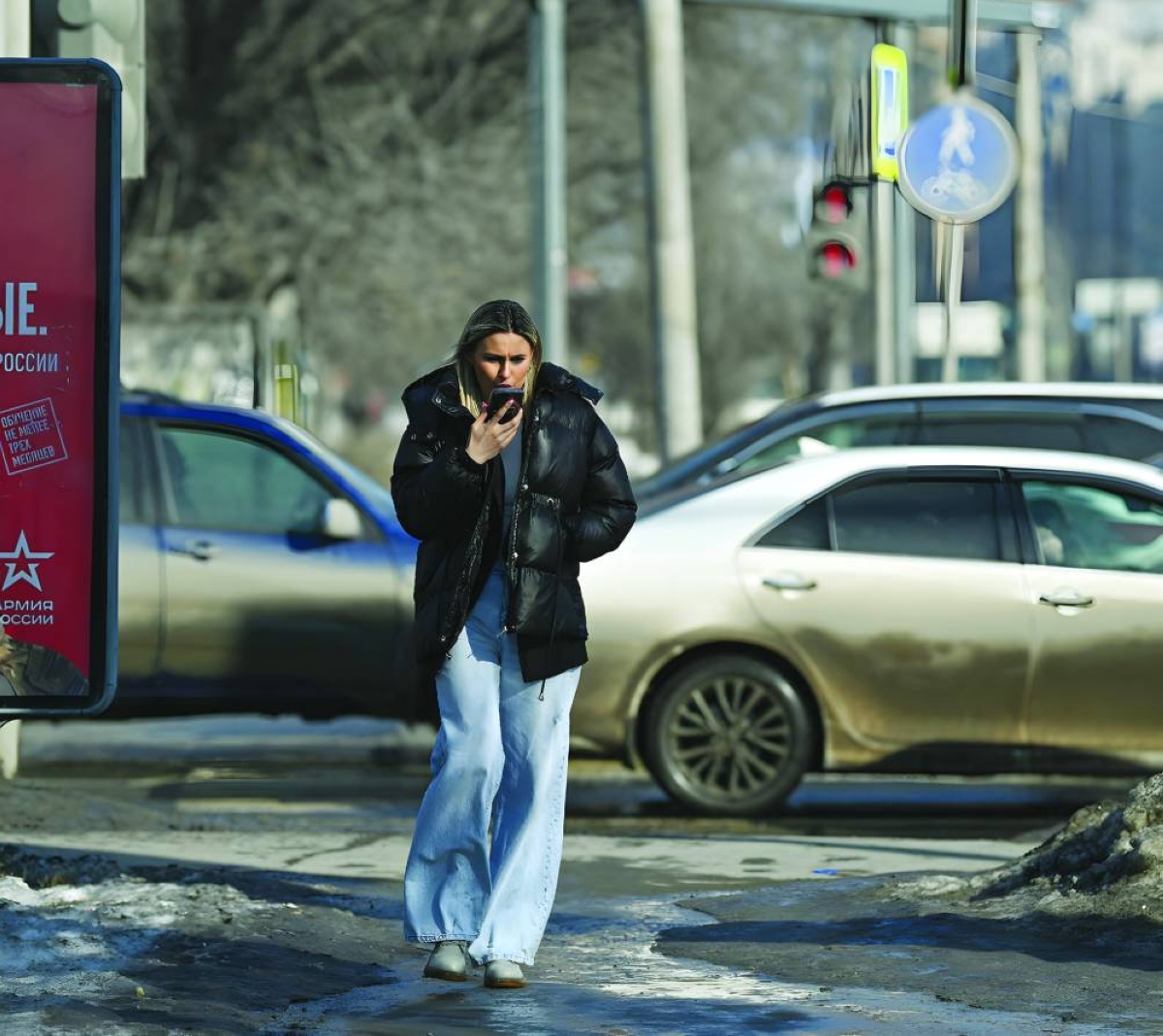 
File photo shows a woman speaking on a phone as she walks past an advertising board, in Omsk, Russia. (Reuters) 