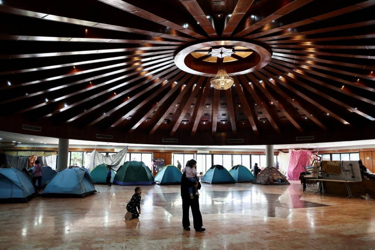A woman holds a child in a school turned into a shelter for displaced families, in Dekwaneh, Lebanon. – Reuters