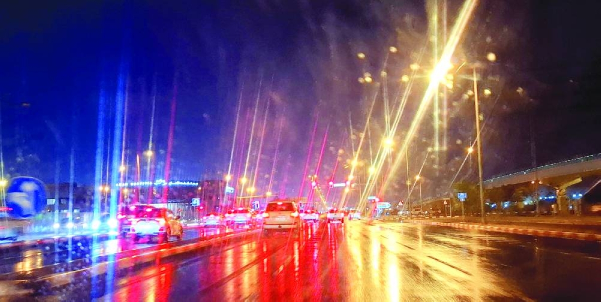 Rain covers a busy road at night, as traffic lights and car headlights shine across the wet surface, creating colourful reflections through a rain-speckled windshield. 
PICTURE: Thajudheen