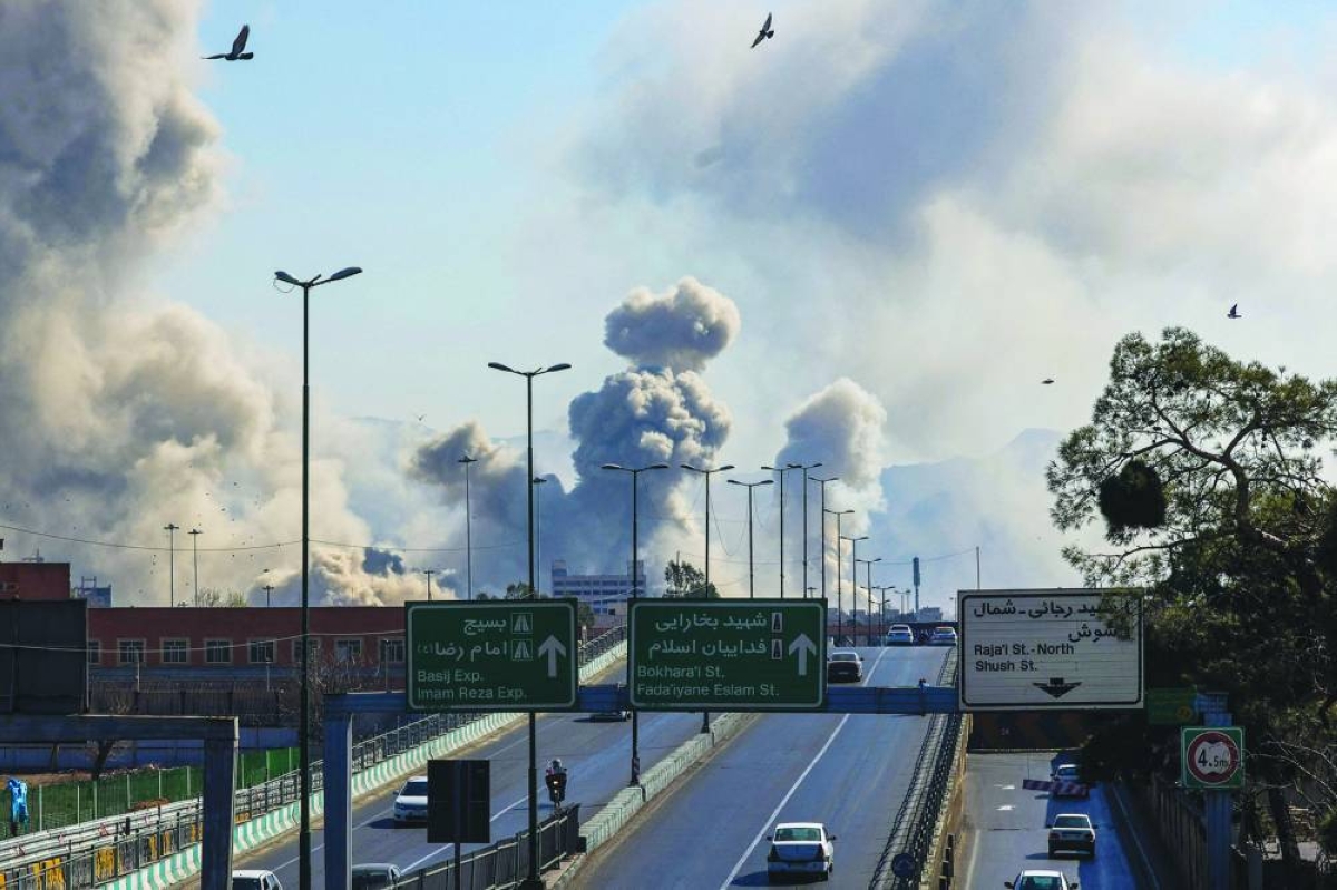 This picture taken on March 5 shows motorists along an expressway as plumes of smoke rise after an air strike in Tehran. – AFP