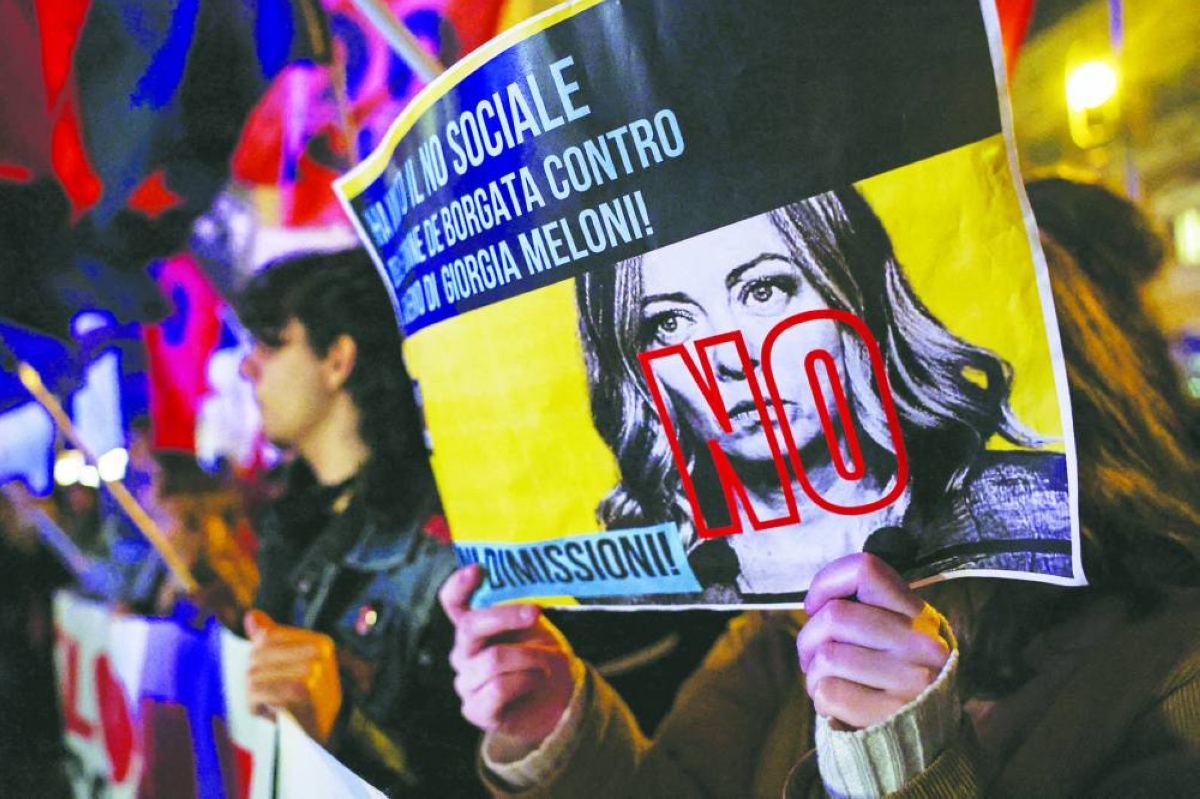 
A person holds a placard depicting Prime Minister Giorgia Meloni crossed with the word “No” as supporters of the “No” to the constitutional referendum on justice reform celebrate their victory in Rome. (Reuters) 