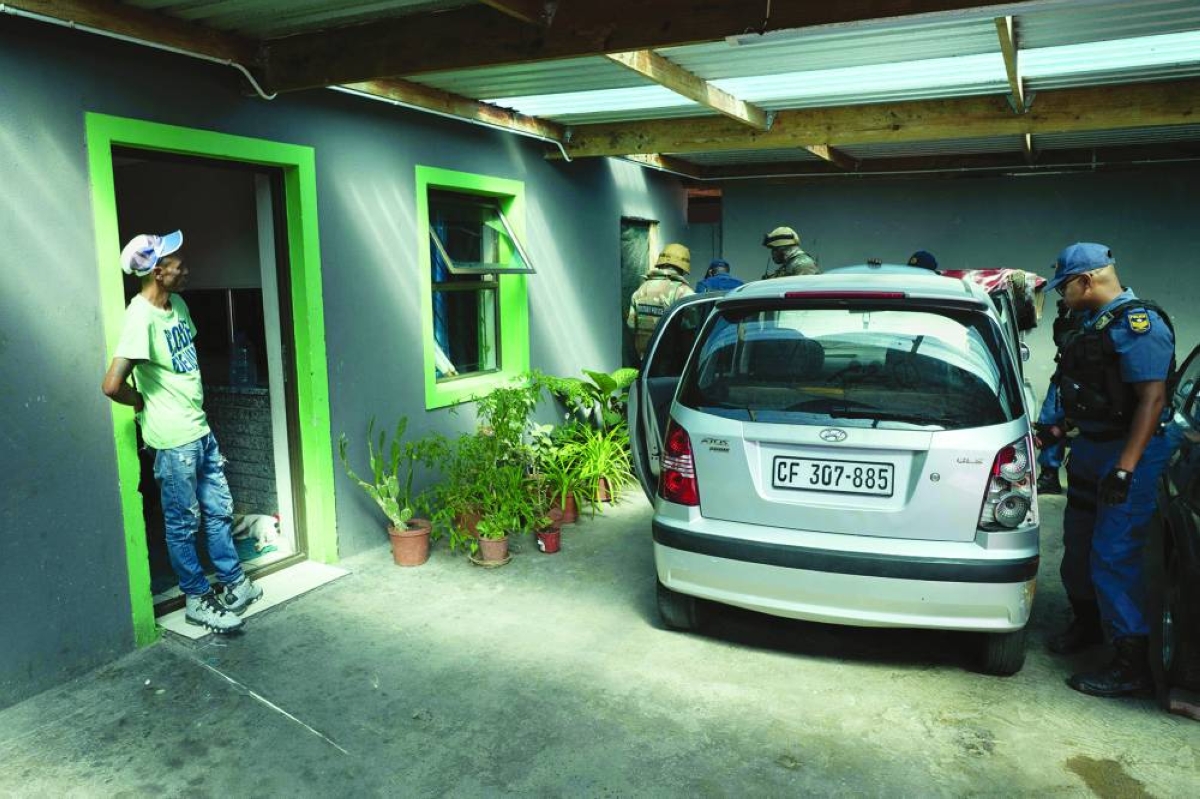 A man watches as soldiers of the South African National Defence Force (SANDF) assist South African Police Service (Saps) officers (right) in searching a car as part of Operation Prosper in Mitchells Plain, near Cape Town, Wednesday. (AFP)