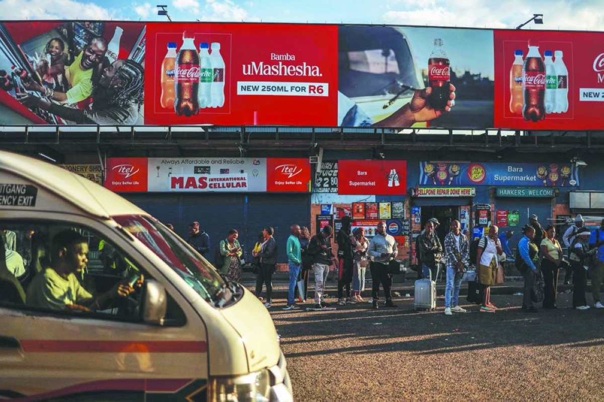 Commuters queue to board a minibus taxi at Bara Taxi rank in Soweto, Wednesday. (AFP)