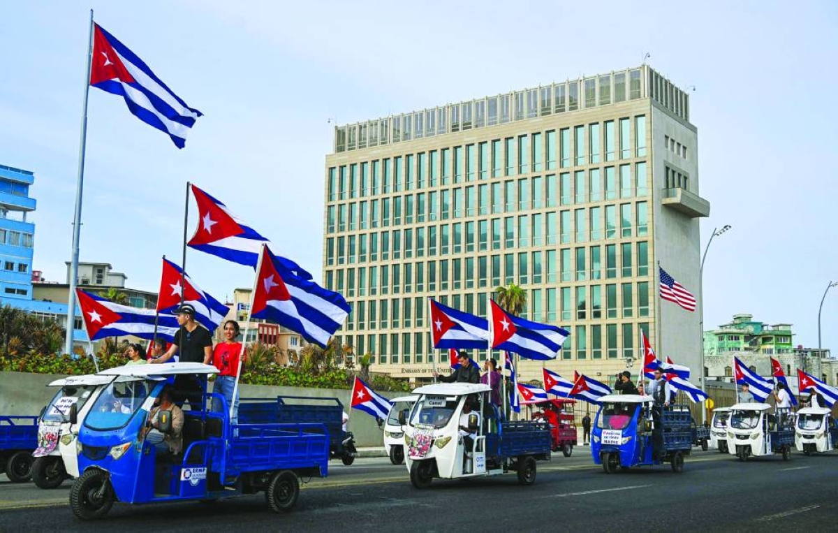 Cubans on electric tricycles decorated with Cuban flags ride past the US embassy during the anti-imperialist youth march in Havana on April 2, 2026. (AFP)