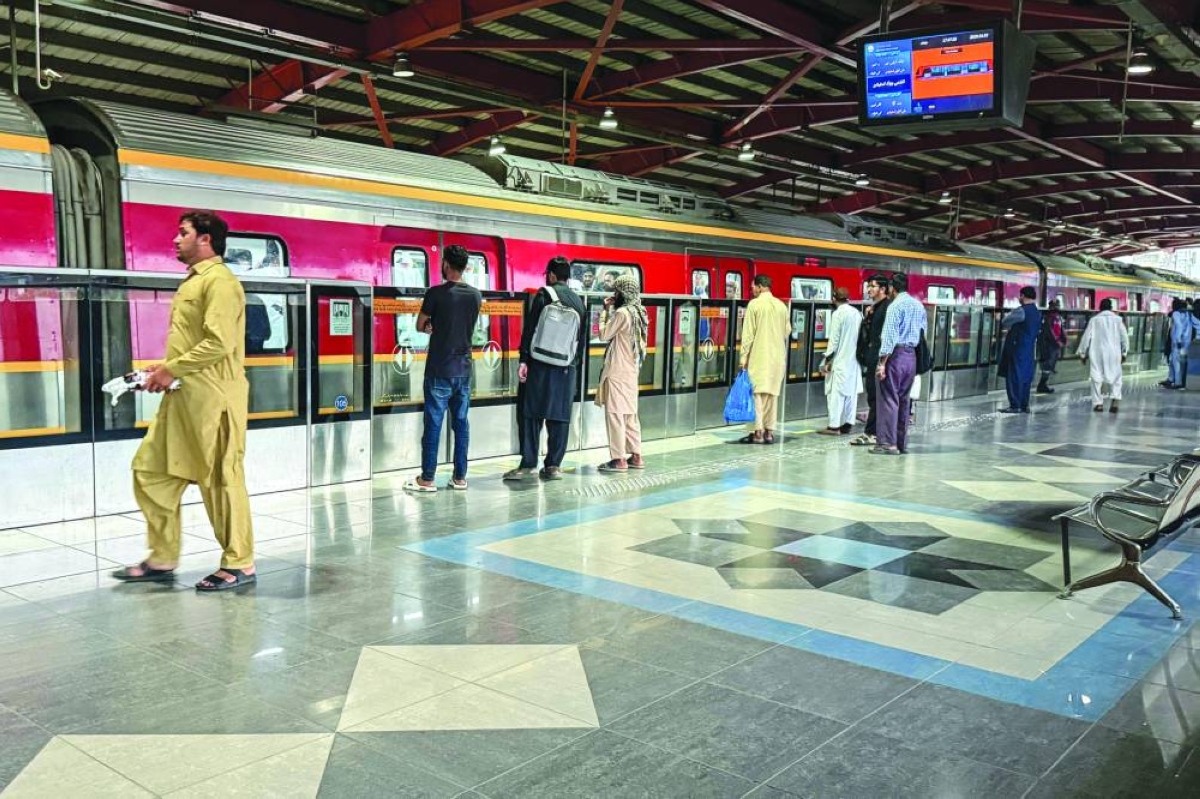Passengers stand on a platform waiting to board the metro at a train station in Lahore yesterday. (AFP)