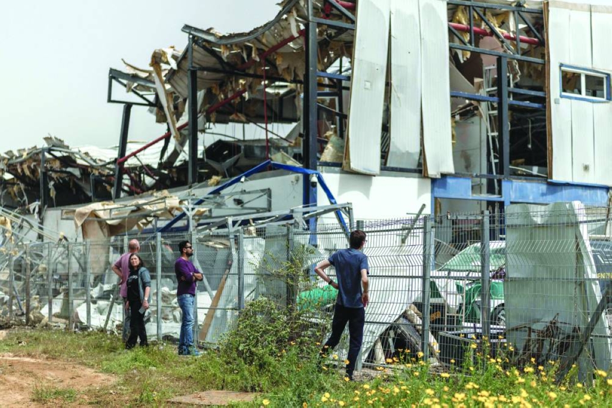 
People look at the damage at a factory that got hit by a missile in Petah Tikva, east of Tel Aviv, Israel, yesterday. (AFP) 
