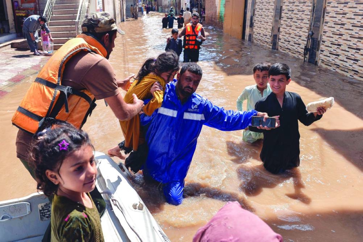 A rescue team helps residents evacuating the flooded area following heavy rainfall on the outskirts of Peshawar Saturday. (AFP)