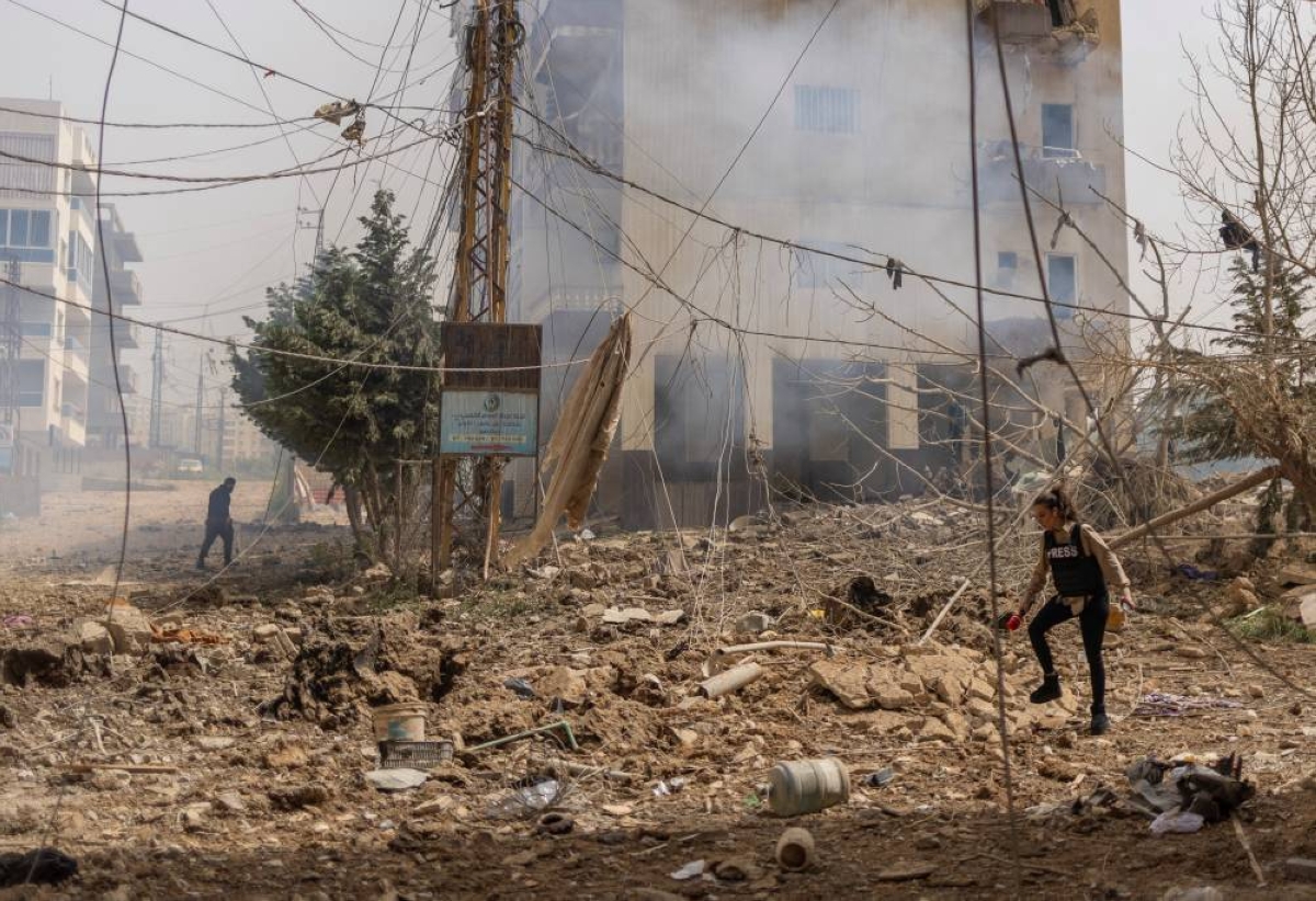 A member of the media walks near a damaged building in the aftermath of an Israeli strike, amid escalating hostilities between Israel and Hezbollah, as the US-Israeli conflict with Iran continues, in Tyre, Lebanon, yesterday. (Reuters)