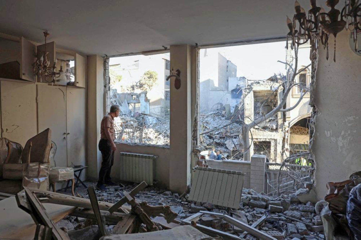 An Iranian resident looks out the window of his damaged home after Israeli-American strikes destroyed residential buildings in Tehran, Tuesday. (AFP)