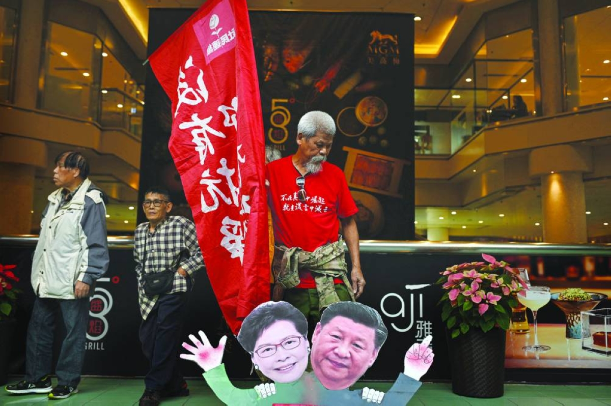 Koo Sze Yiu stands behind placards of Chinese President Xi Jinping and Hong Kong Chief Executive Carrie Lam during a protest before trying to board a ferry to Macau, in Hong Kong. (AFP/File photo)