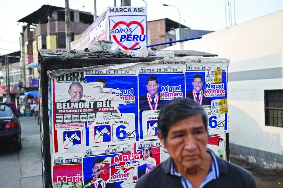 A man waits for a bus next to political propaganda in the Villa Maria del Triunfo neighborhood in Lima, Wednesday. (AFP)