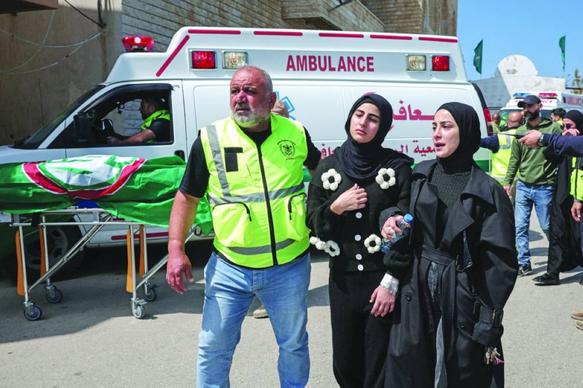 
Family members are escorted to follow the bodies, transported by ambulances to the burial site, during the funeral service of six women and a man killed in Israeli strikes in Abbasiyeh, in Tyre, Lebanon, yesterday. (Reuters) 