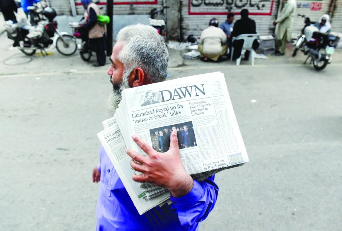 A man carrying a bundle of newspapers with a headline that reads, "Islamabad keyed up for 'make-or-break' talks", walks along a street, as delegations from the United States and Iran are expected to hold peace talks, in Lahore, Pakistan, April 11, 2026. REUTERS