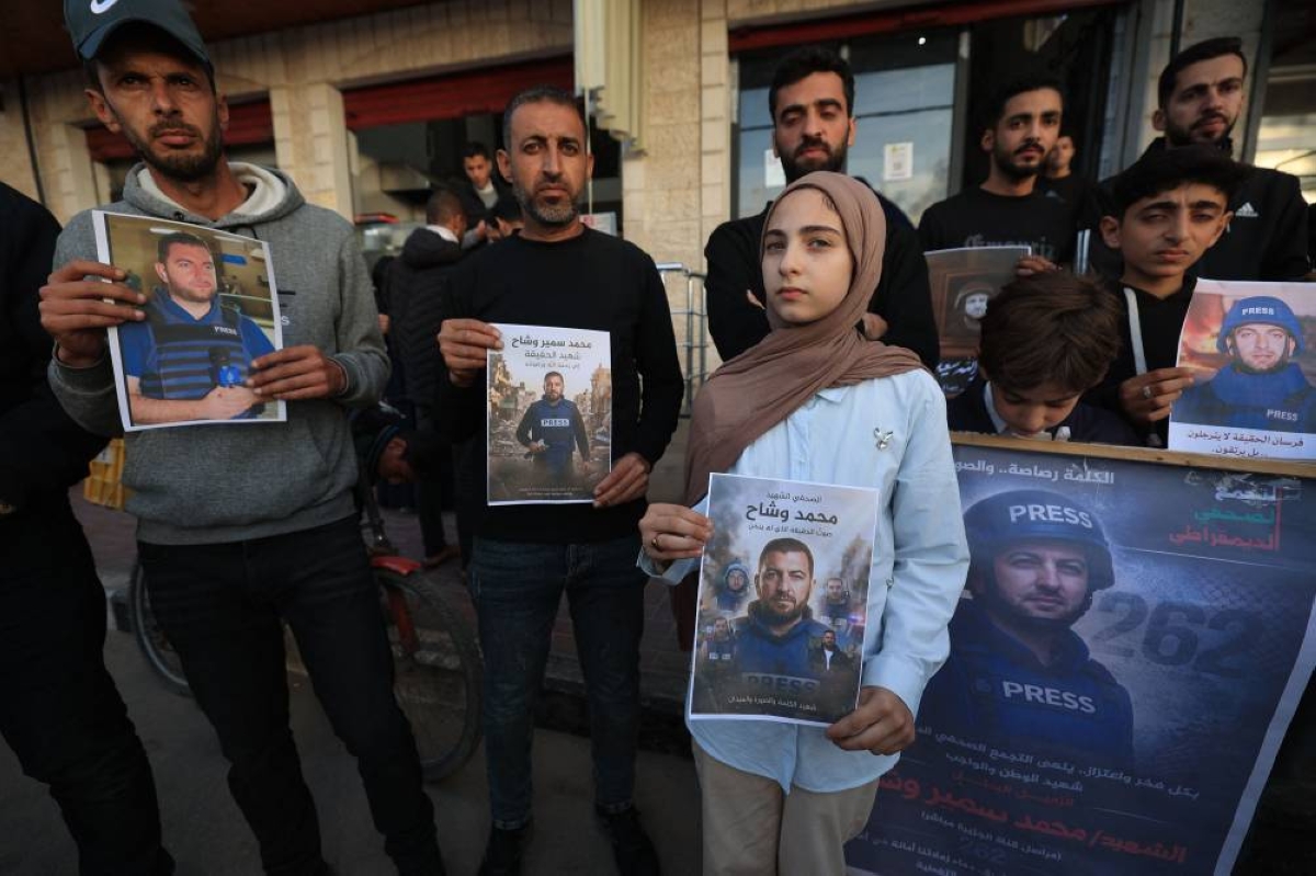 Fifteen-year-old Samia stands with Palestinians as they gather, holding images of her father, Mohammed Wishah, a journalist for the Qatar-based broadcaster Al-Jazeera Mubasher who was killed in an Israeli attack in the Bureij Refugee Camp on April 8, during a solidarity rally in Deir al Balah in the Gaza Strip on April 11, 2026. The Israeli military said on April 9, 2026, that an Al Jazeera journalist killed a day earlier in an Israeli strike in Gaza was a Hamas militant who had "operated under the guise of a journalist". (Photo by Eyad Baba / AFP)