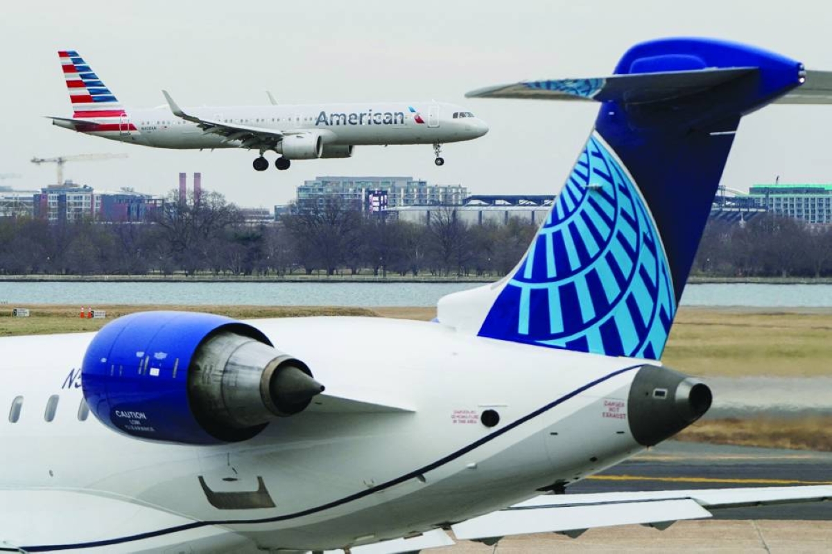 An American Airlines aircraft flies past the tail of a United Airlines aircraft as it lands at Reagan National Airport in Arlington, Virginia. A potential deal between United Airlines and American Airlines will create an industry behemoth and invite extraordinary scrutiny from regulators, labour unions and consumer advocates, all wary of higher fares ‌and reduced competition. (File Picture)