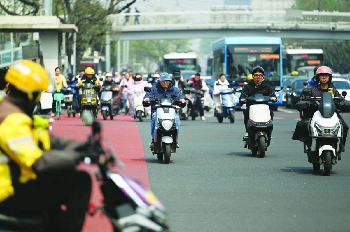 People riding electric bicycles cross a street in Beijing on Wednesday. China’s growth likely rebounded in the first quarter of 2026, offering policymakers time to assess the impact of the Iran war on the world’s second-largest economy before stepping in with stimulus.