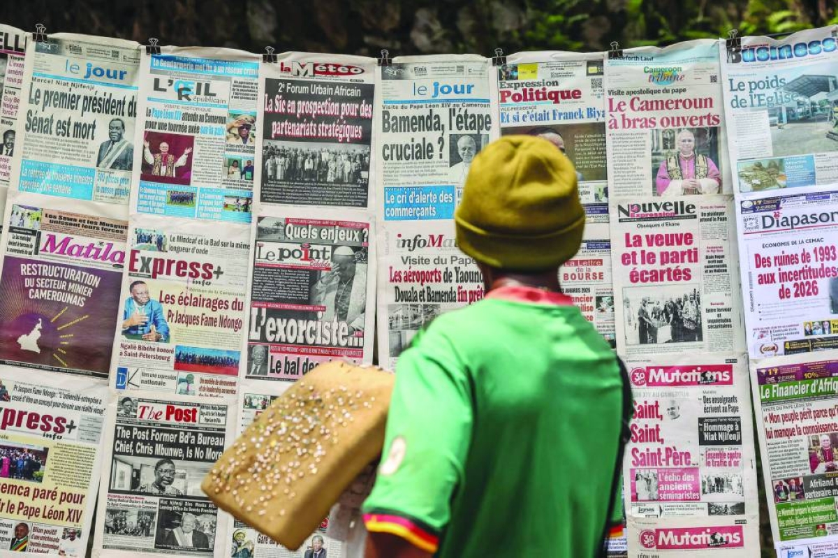 A resident reads newspapers showing articles about Pope Leo XIV’s visit at a newsstand in Yaounde. – AFP