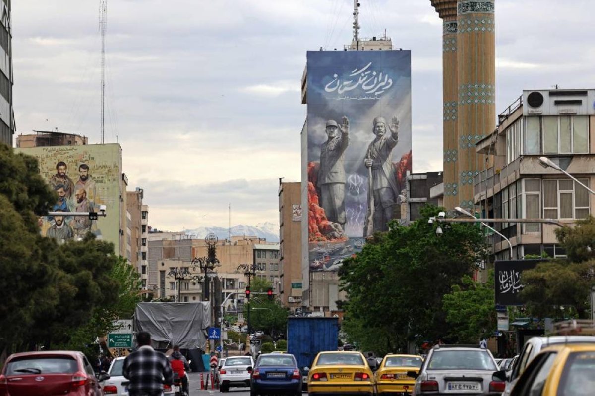 Commuters drive past a giant billboard referring to the 'Strait of Hormuz' along a busy street in Tehran on April 19, 2026. The strategic Strait of Hormuz was again closed on April 19 in the stand-off between Iran and the United States, with Iran's powerful parliament speaker signalling a final peace deal remained "far" off despite some movement in negotiations. (Photo by ATTA KENARE / AFP) / 