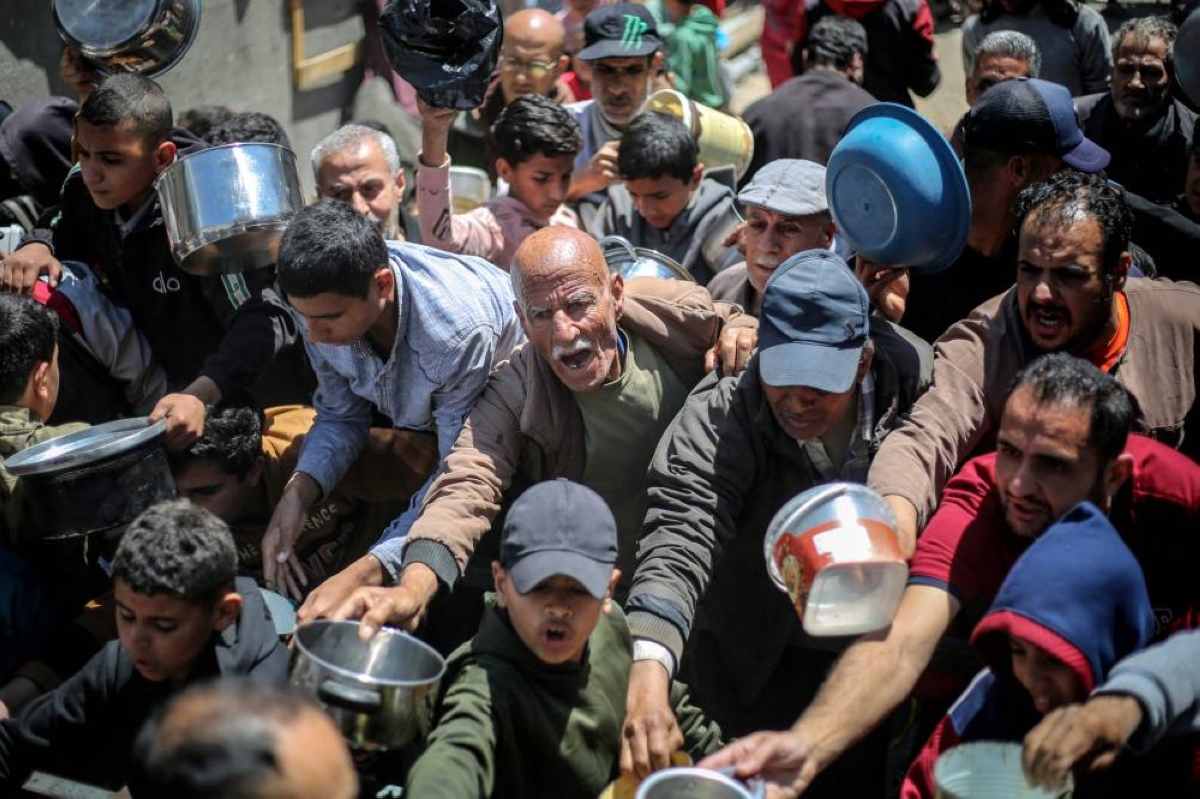 TOPSHOT - Displaced Palestinians receive food from a charity kitchen at the Nuseirat refugee camp in the central Gaza Strip on April 22, 2026. Since the terms of a US-brokered ceasefire deal came into effect on October 10, Israel remains in control of nearly half of the Gaza Strip, including all its border areas. Nearly two million people in Gaza are living in makeshift shelters, and the humanitarian situation remains dire, according to aid agencies. (Photo by Eyad Baba / AFP)