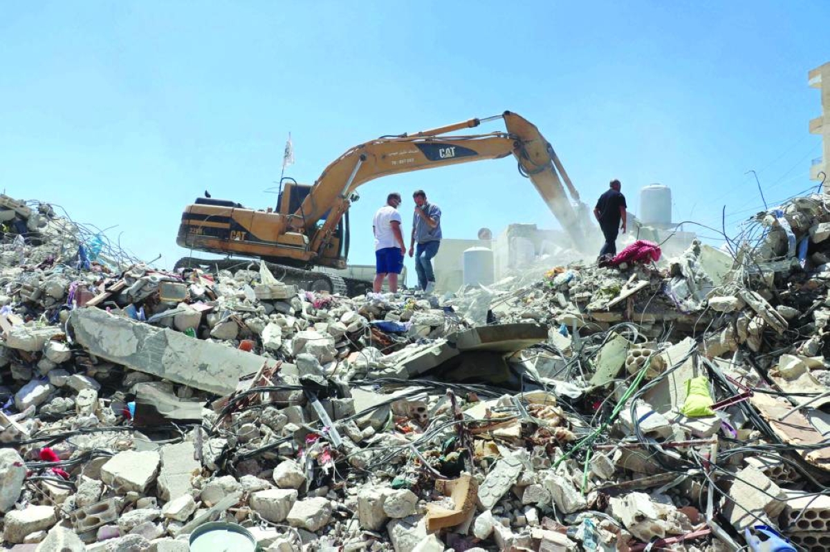 Resident Mohamad Ali Hijazi (left) stands next to an excavator clearing the rubble of destroyed buildings at a residential area in Tyre. – AFP