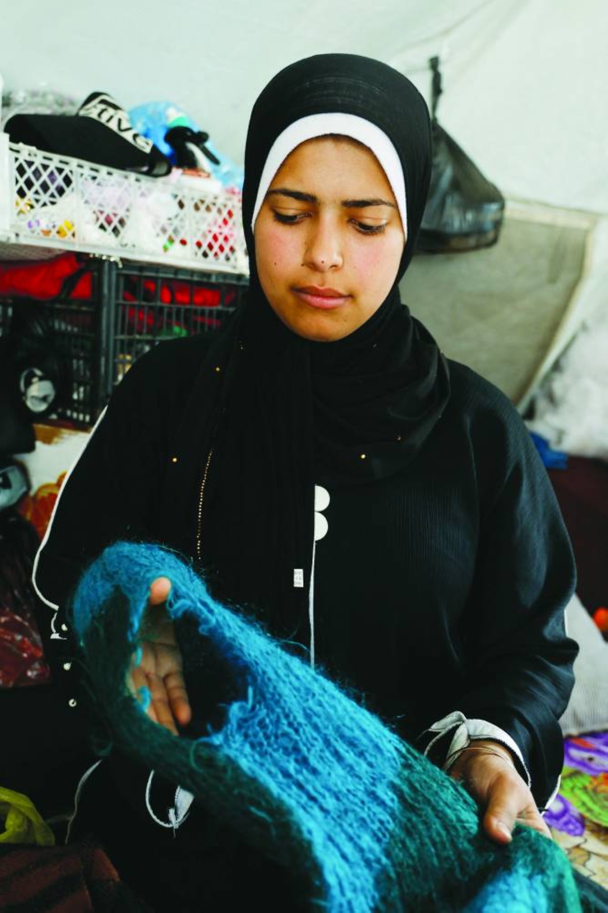 Palestinian bride-to-be Amani Abu Selmi holds damaged wool clothes inside a tent, after they were bitten by rodents, in Khan Younis in the southern Gaza Strip. – Reuters