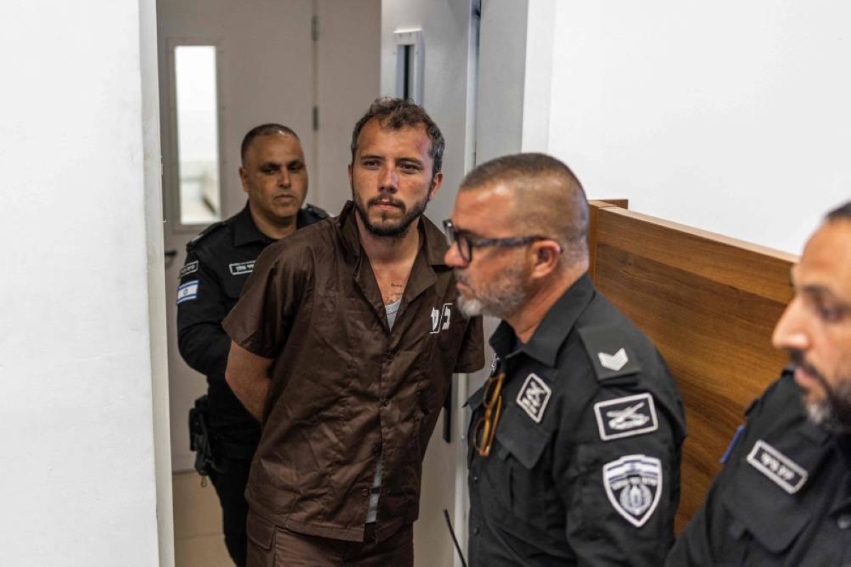 TOPSHOT - Security personnel escort Brazilian activist Thiago Avila to a court in Ashkelon on May 3, 2026. Two foreign activists from a Gaza-bound flotilla who were brought to Israel for interrogation appeared before an Israeli court on May 3, a rights group defending them told AFP. The flotilla of more than 50 vessels had set sail from France, Spain and Italy with the aim of breaking an Israeli blockade of Gaza and bringing supplies to the devastated Palestinian territory. (Photo by Ilia YEFIMOVICH / AFP)