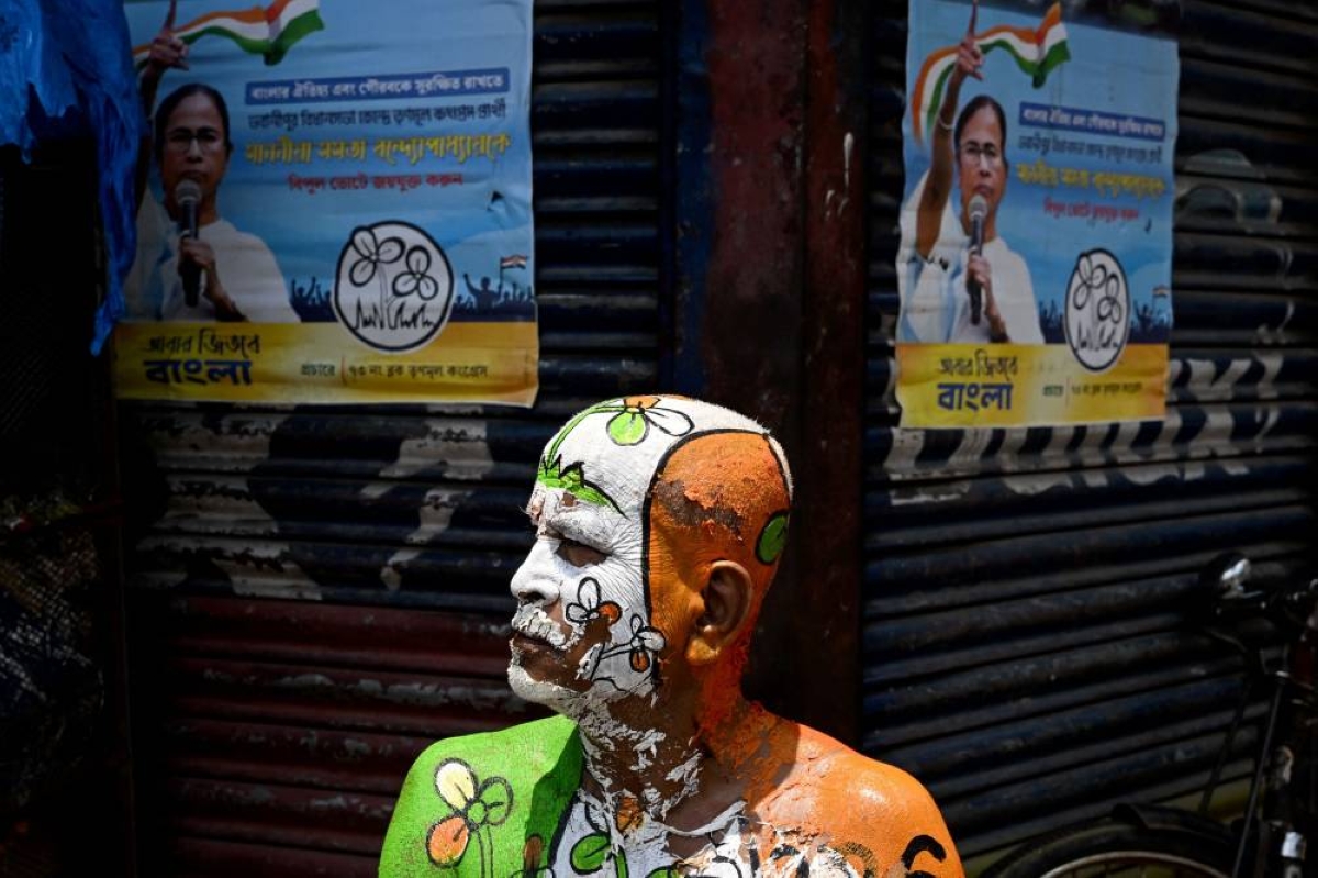 A supporter with the All India Trinamool Congress (TMC) party election symbol painted on his body sits next to posters of West Bengal chief minister and party chairperson Mamata Banerjee, along a street near her residence in Kolkata on May 4, 2026 during vote counting for the West Bengal Legislative Assembly elections. Vote counting in key Indian state elections was underway on May 4 under tight security, with the focus on West Bengal, where Prime Minister Narendra Modi's party is hoping for crucial gains. (Photo by Dibyangshu SARKAR / AFP)