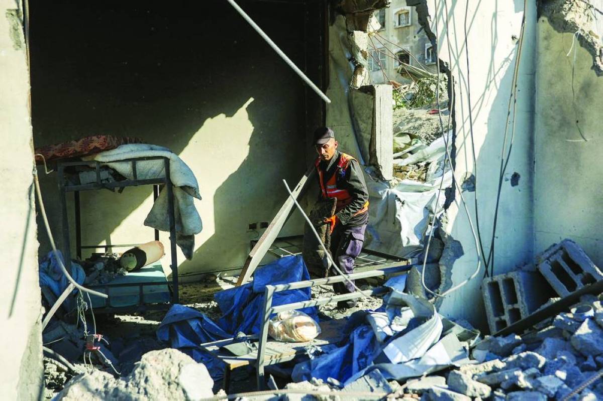 A first responder inspects the site of an Israeli strike on a police station in Gaza City on May 5, 2026. (Photo by Omar AL-QATTAA / AFP)