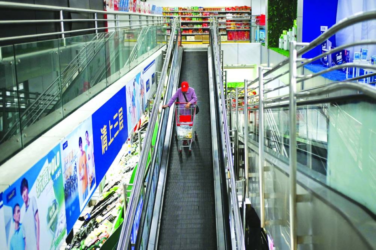 A man goes down an escalator at a supermarket in Beijing. China's consumer prices ticked up in April as the cost of crude oil rose globally due to the Iran war, official data showed Monday.